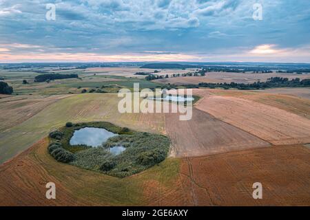 Luftdrohnenaufnahme von kleinen Teichen auf Feldern auf dem Land bei Sonnenuntergang Stockfoto