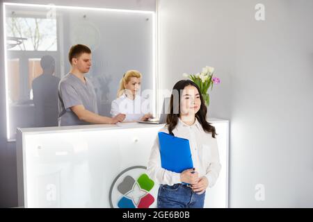 Ein junges hübsches Mädchen kam in die Klinik und sprach mit Ärzten an der Rezeption Stockfoto