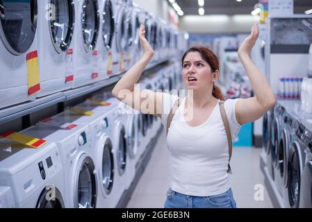 Kaukasische Frau wählt eine Waschmaschine in einem Haushaltswarenladen Stockfoto