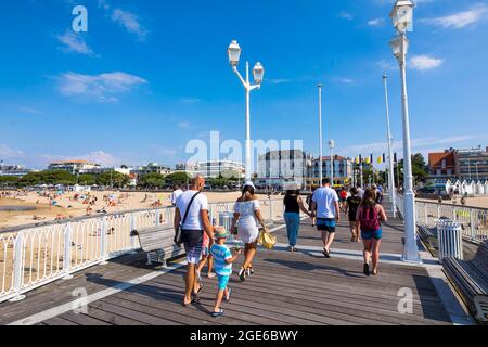 Arcachon (Südwestfrankreich): Touristen auf dem Pier „Jetee Thiers“, blaue, weiße und gelbe Flaggen der Stadt Arcachon und Gebäude entlang der Wa Stockfoto