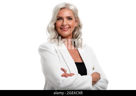 Studio-Porträt einer grauhaarigen älteren Frau, die auf die Kamera schaut und lächelt, während sie auf einem isolierten weißen Hintergrund steht. Speicherplatz kopieren. Stockfoto