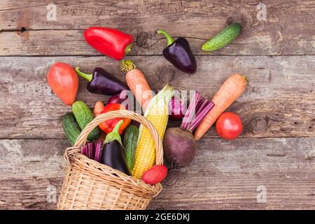 Gemüse in einem Korbkorb auf einem Holzhintergrund. Frische Feldfrüchte, landwirtschaftliche Produkte, ein Gemüsegarten zu Hause. Speicherplatz kopieren Stockfoto