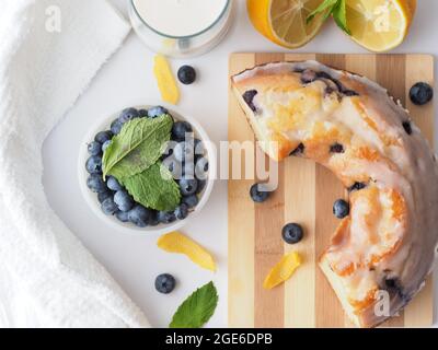 Flache Verlegung der Hälfte des Blaubeer-Bunte-Kuchens auf Holzdiele mit Requisiten Stockfoto