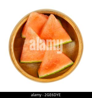 Wassermelonenscheiben, in einer Holzschale. Dreieckige und verzehrfertige Stücke einer frisch geschnittenen, reifen und kernlosen Frucht von Citrullus lanatus. Stockfoto