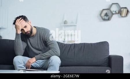 Gestresster Mann schaut weg, während er in der Nähe von Ordner auf Couchtisch sitzt Stockfoto