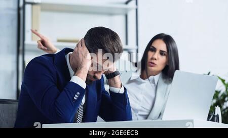 Frustrierter Geschäftsmann, der beim Streit im Büro fast unscharf mit dem Finger zeigt Stockfoto