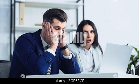 Verärgert Geschäftsmann mit geschlossenen Augen in der Nähe verschwommene Geschäftsfrau Streit im Büro Stockfoto