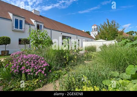 Neuhardenberg, Deutschland. August 2021. Im Garten der Orangerie von Schloss Neuhardenberg blühen Blumen, im Hintergrund die Schinkel-Kirche. Quelle: Patrick Pleul/dpa-Zentralbild/ZB/dpa/Alamy Live News Stockfoto