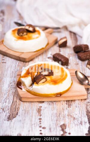 Vanillepanna Cotta mit Karamell auf rustikalem Holztisch. Italienisches Dessert mit gesüßter Creme, mit Gelatine verdickt Stockfoto