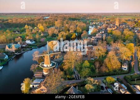 Niederlande, Loenen aan de Vecht, Windmühle im Dorfzentrum entlang des Flusses Vecht. Antenne. Feder. Stockfoto