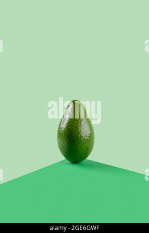 Frische grüne Avocado Gemüse Food Balance auf grünem geometrischen Papier Hintergrund, vegetarische und vegane Ernährung balancieren kreative Lebensmittelkonzept, Copy Space Stockfoto