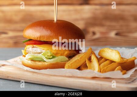 Frische Burger- und Kartoffelkeile auf grauem Holzhintergrund Stockfoto