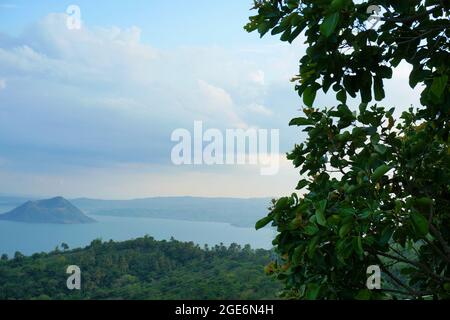 Bäume und Landschaften im Vordergrund und der Vulkan Taal im Hintergrund in Batangas, Philippinen Stockfoto