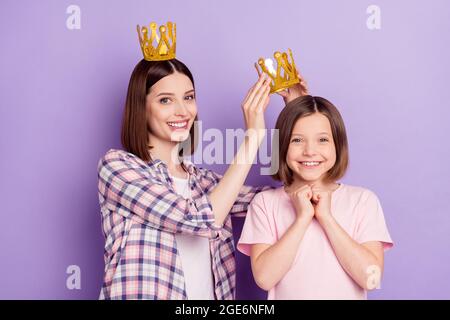 Portrait von zwei attraktiven fröhlichen Mädchen tragen Krone mit Spaß Geburtstagsfeier isoliert über lila violette Farbe Hintergrund Stockfoto