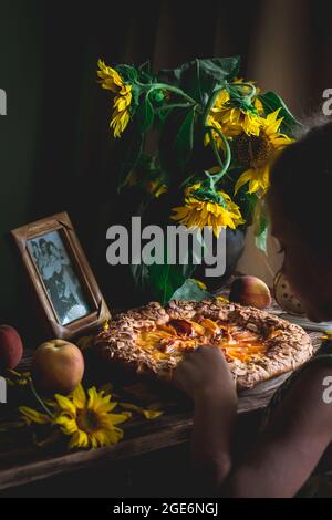 Galette mit Pfirsichen. Ein Teil der Galette und Sonnenblumen im Fokus Stockfoto