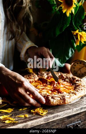 Galette mit Pfirsichen. Ein Teil der Galette und Sonnenblumen im Fokus Stockfoto