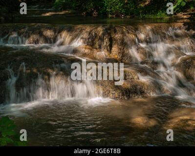 Das klare Wasser fließt über die braunen Felsen im Bach Stockfoto