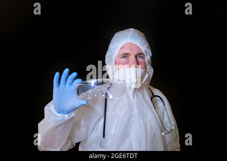 Medic im covid Schutzanzug mit Maske und Brille Narben auf seinem Gesicht, schwarzer Hintergrund Stockfoto