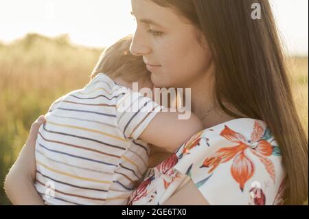 Nahaufnahme Porträt der schönen jungen Mutter hält ihren kleinen Sohn in den Händen und kümmert sich um ihn Stockfoto