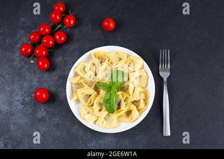 Hausgemachte vegetarische italienische Tortelloni mit dekoriert mit frischem Basilikum und Tomaten auf einem Teller. Italienische Küche Stockfoto