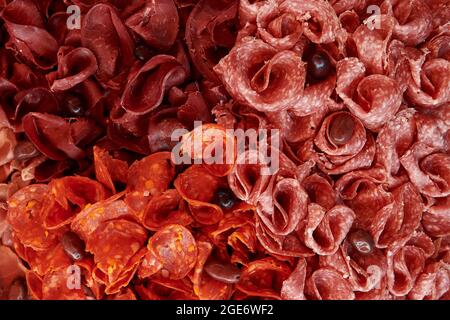 Drei Fleischsorten, die mit Oliven verziert sind. Chorizo, Salami und Rindfleisch treffen auf Scheiben. Wunderschöner Hintergrund für das Essen. Erstklassiges Catering. Blick von oben. Stockfoto