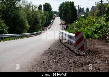 Rote Straßenreflektoren entlang der Straße. Metalleinzäunung von Barriere-Typ, Nahaufnahme. Straßen- und Verkehrssicherheit. Reflektierende Farbe auf dem Schild. Mittlere Barriere Stockfoto