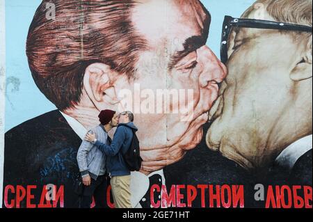 22.09.2014, Berlin, Deutschland, Europa - zwei junge Männer küssen sich vor dem berühmten Wandgemälde an der Berliner Mauer in der East Side Gallery in Friedrichshain. Stockfoto