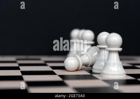 Weiße Schachfigur fällt auf schwarzen Hintergrund Stockfoto