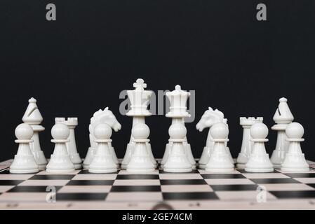 Row of White Chess Set - Einheits- und Teamwork-Konzept - Weiße Schachfiguren auf schwarzem Hintergrund Stockfoto