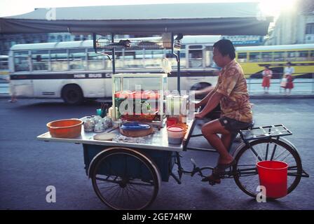 Malaysia. Penang. Ein Einheimischer tritt mit seinem Dreirad an den Lebensmittelautomaten. Stockfoto