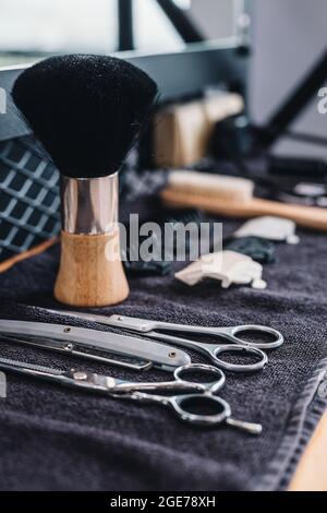 Nahaufnahme Rasierpinsel, Rasiermesser, Schere, Kämme auf dem Tisch auf einem schwarzen Handtuch. Professionelle Barbier Werkzeuge und Ausrüstung. Barbershop. Professionelle Herren s Stockfoto