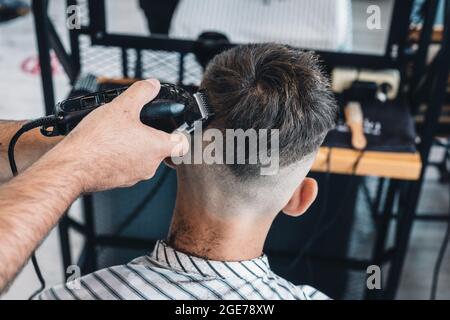 Professionelle Frisur und Styling für Herren in einem Friseursalon oder Friseursalon. Barber gibt einem Teenager einen trendigen Haarschnitt. Nahaufnahme. haarpflege Stockfoto