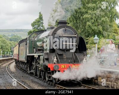 Ein Dampfzug, der von der Dampflok Nr. 825 der S15-Klasse gezogen wurde, wird mit einem Zug von Whitby nach Pickering auf der North York Moors Railway von Grosmont Staion abfahren. Stockfoto