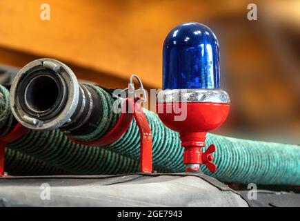 Nahaufnahme eines blauen Lichts und eines Löschschlauchs auf dem Dach eines antiken Feuerwehrmotors Stockfoto