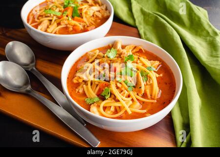 Kubanische Hühnernudelsuppe garniert mit Cilantro: Schalen mit Hühnernudelsuppe in einer Tomatenbrühe Stockfoto