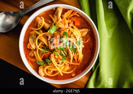 Kubanische Hühnchen-Nudelsuppe garniert mit Cilantro: Schüssel Hühnchen-Nudelsuppe in einer Tomatenbrühe Stockfoto