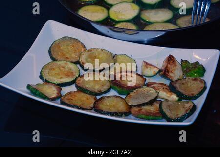 Zucchini gebraten in Öl in einer Pfanne und auf einem Teller bereit, als Vorspeise zu essen Stockfoto