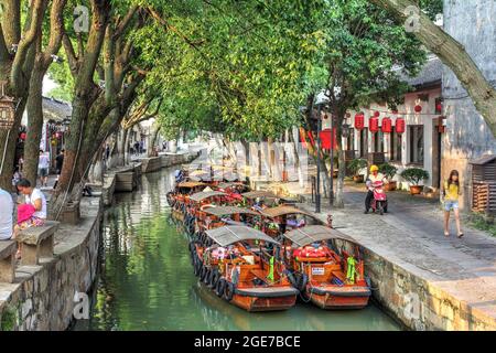 Abendszene in Tongli, einer wunderschönen Wasserstadt in der Nähe von Suzhou, Provinz Jiangsu, China, mit einem der mit Bäumen bedeckten Kanäle und traditionellen Boa Stockfoto