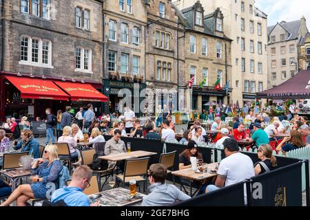 Edinburgh, Schottland, Großbritannien. August 2021. Die Nachrichten, dass Lieferkettenprobleme in Schottland zu einem Biermangel führen könnten, haben viele Besucher in der Altstadt von Edinburgh nicht davon abschrecken lassen, einen warmen Nachmittag bei Sonnenschein in einer der vielen Bars im Freien der Stadt zu genießen. Bild: Die Biergärten in Grassmarket waren sehr voll. Iain Masterton/Alamy Live Nachrichten. Stockfoto