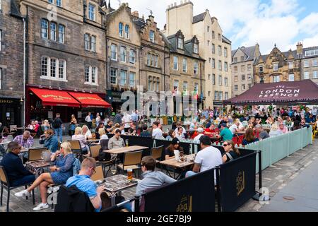 Edinburgh, Schottland, Großbritannien. August 2021. Die Nachrichten, dass Lieferkettenprobleme in Schottland zu einem Biermangel führen könnten, haben viele Besucher in der Altstadt von Edinburgh nicht davon abschrecken lassen, einen warmen Nachmittag bei Sonnenschein in einer der vielen Bars im Freien der Stadt zu genießen. Bild: Die Biergärten in Grassmarket waren sehr voll. Iain Masterton/Alamy Live Nachrichten. Stockfoto