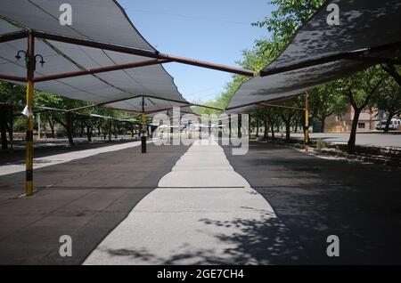 Parkplatz für Autos unter Stoffdach. Kommunaler Parkplatz in der Nähe der Stadt Mendoza, Argentinien. Parkplätze unter dem Vordach im Schatten Stockfoto