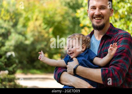 Junger Vater hält Baby Mädchen in den Armen, glückliche Familie. Vater und Tochter lachen fröhliche Gesichter Stockfoto