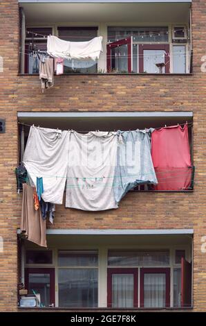 Das Waschen wurde zum Trocknen an Wäscheleinen aufgehängt, die auf den Balkonen eines Wohnhauses in den Niederlanden aufgereiht waren Stockfoto