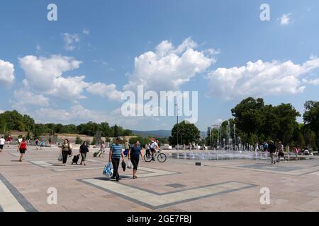 NIS, Serbien - 14. August 2021 Stadtplatz mit gepflastertem Boden und Brunnen, Menschen gehen an einem heißen sonnigen Sommertag in der Stadt Nis Stockfoto