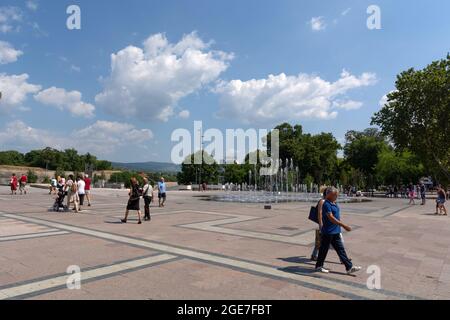 NIS, Serbien - 14. August 2021 Platz mit gepflastertem Boden und Brunnen, Menschen gehen an einem heißen sonnigen Sommertag in der Stadt Nis Stockfoto