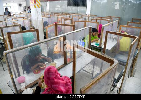 Dhaka, Bangladesch. August 2021. Mitarbeiter von Ready-Made Garment (RMG) speisen in der Bekleidungsfabrik Civil Engineering Limited in Dhaka getrennt durch Polyethylenfolien als Sicherheitsmaßnahme zur Reduzierung der Ausbreitung des Coronavirus. (Foto von Piyas Biswas/SOPA Images/Sipa USA) Quelle: SIPA USA/Alamy Live News Stockfoto