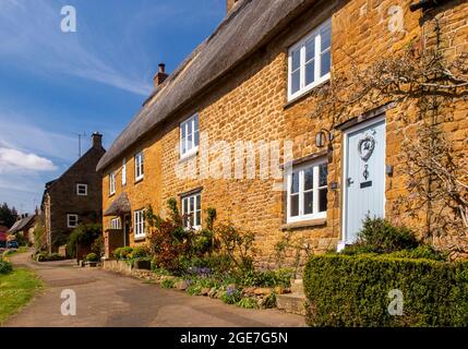 Großbritannien, England, Oxfordshire, Wroxton, Main Street, Hübsche reetgedeckte Cotswold-Steinhütten Stockfoto