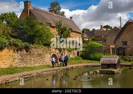 Großbritannien, England, Oxfordshire, Wroxton, Besucher, die am Rande des Dorfes Ententeich spazieren Stockfoto