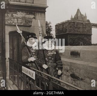 Zwei „Beefeaters“ (Wächter des Tower of London & Kronjuwelen, Großbritannien) auf Raleighs Walk c1946; (an der erhöhten Wand zwischen dem Bloody Tower und dem Leutnant's House machte er seinen täglichen Spaziergang, als er dort eingesperrt war). Beefeaters sind offiziell bekannt als Yeomen Warders of her Majesty's Royal Palace und Fortress the Tower of London, und Mitglieder der Sovereign's Body Guard der Yeoman Guard außergewöhnlich. Ein Teil der Tower Bridge ist oben rechts auf dem Foto zu sehen. Stockfoto