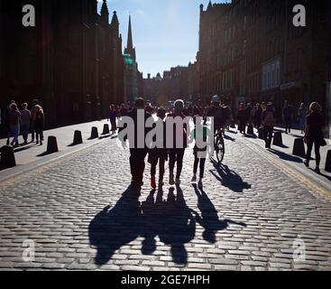 Royal Mile, Edinburgh, Schottland, UK Wetter. August 2021. Sonniger Abend auf der gepflasterten High Street mit Silhouetten umherschwirrenden Menschen, die auf der Suche nach Unterhaltung von den letzten Shows des Tages von Straßenunterhaltern sind. Quelle: Arch White/Alamy Live News Stockfoto